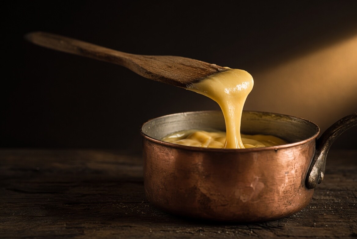 De la pâte à choux qui retombe d'une spatule en bois en formant un V